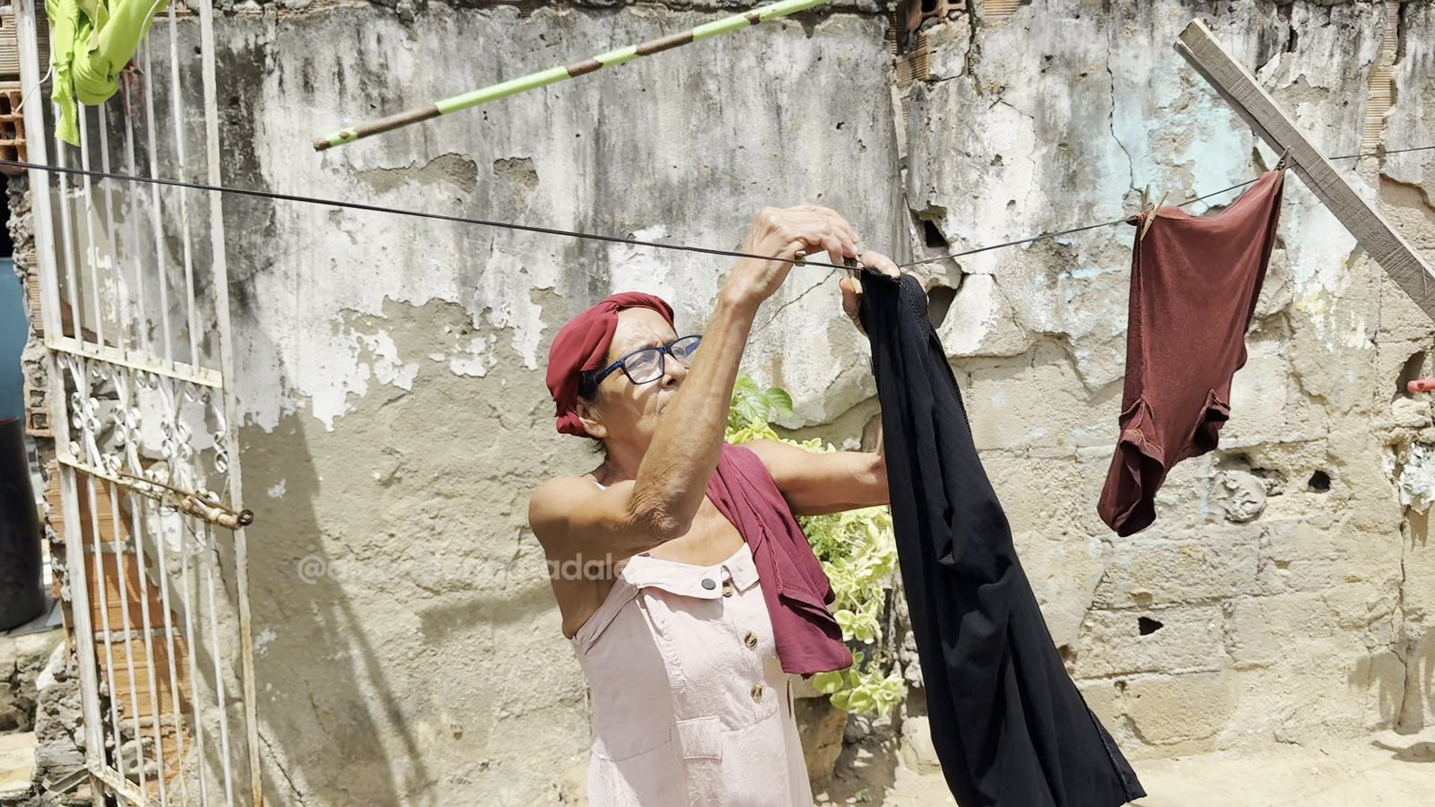 Dona Madalena estendendo roupa no varal